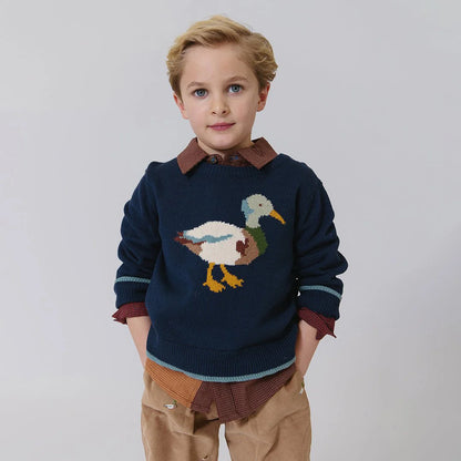 Child wearing a navy sweater with a duck design on a plain background
