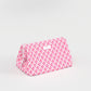Pink and white geometric patterned wedge shaped cosmetic bag on a light gray background