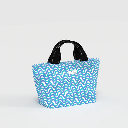 Blue and green wavy patterned bag with black handles on a light gray background