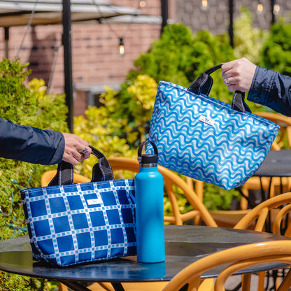 Two blue patterned bags and a blue water bottle on a table outdoors.