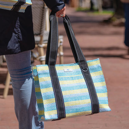 Person holding a striped tote bag with a blurred background