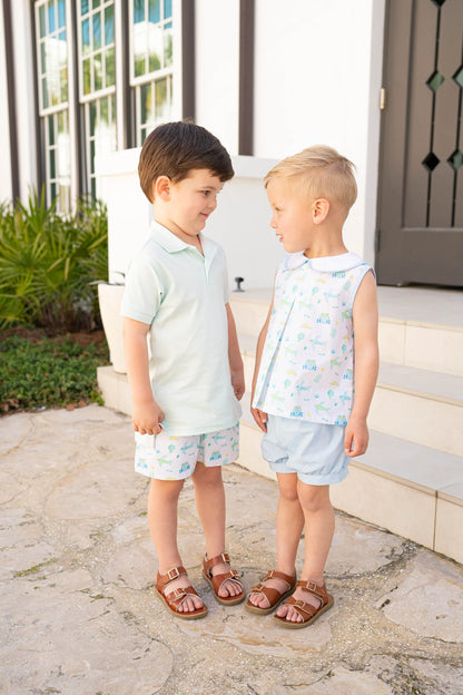Two young boys standing on a stone path in front of a house.
