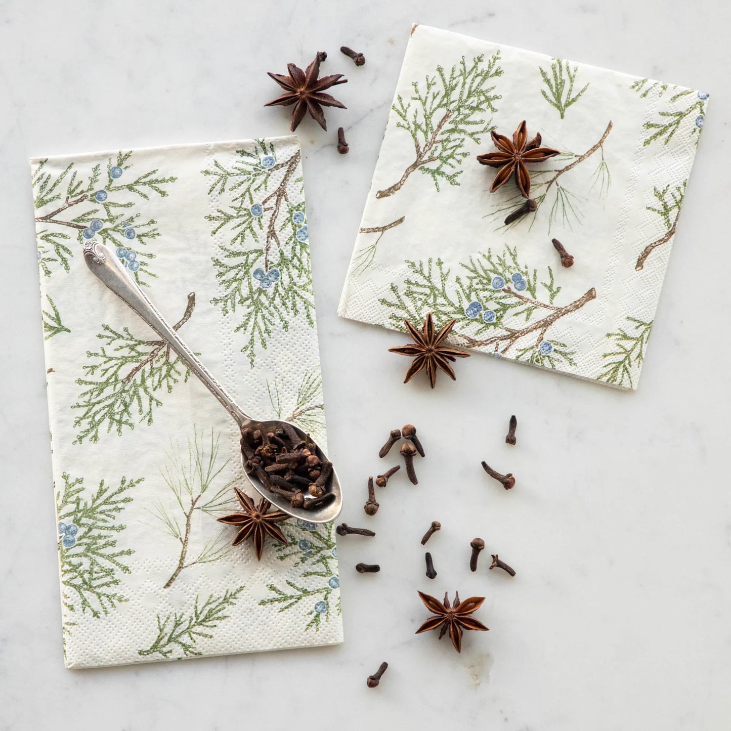Napkins with floral and branch pattern on a marble surface with star anise.