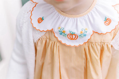 Close-up of a dress with embroidered pumpkin design on a white background