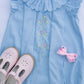Light blue dress with floral embroidery and pink shoes on a white background