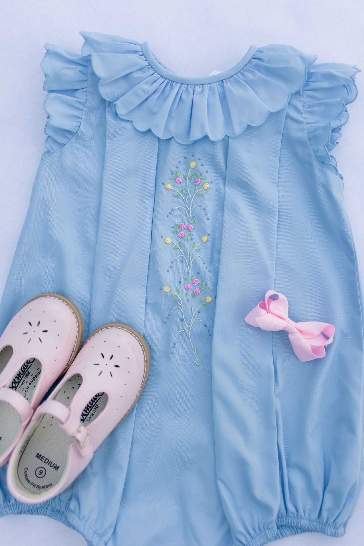 Light blue dress with floral embroidery and pink shoes on a white background