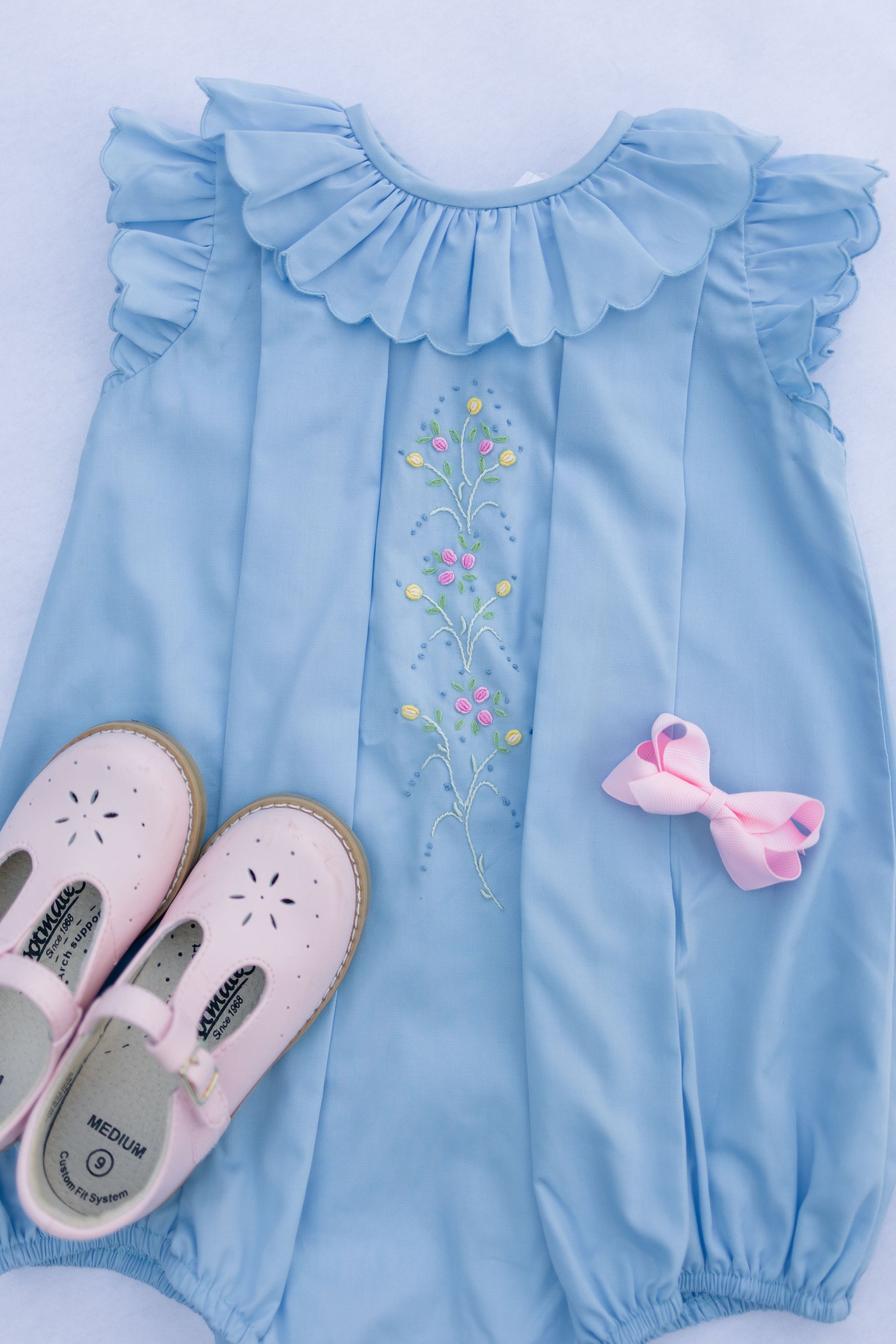Light blue dress with floral embroidery and pink shoes on a white background
