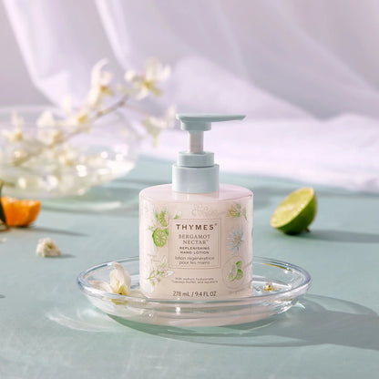 Thymes hand soap bottle on a glass plate with decorative elements on a light blue background
