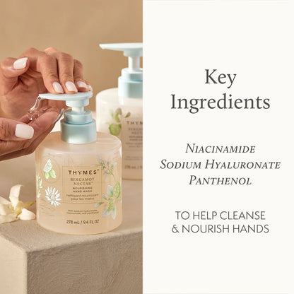 Hand using a Thymes hand wash bottle with key ingredients listed on the side.