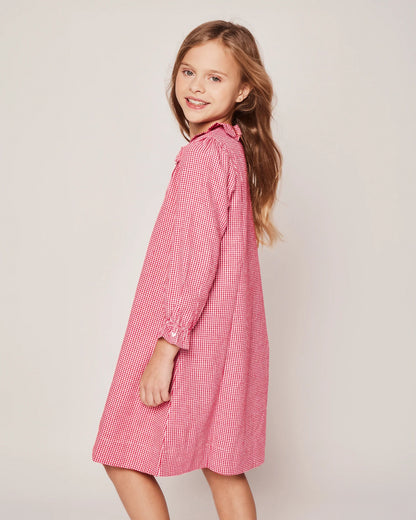 Young girl wearing a pink checkered dress against a plain background