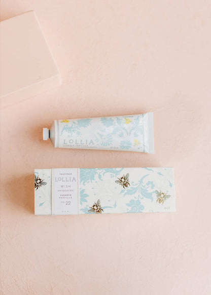 Tube of hand cream and its packaging on a pink background