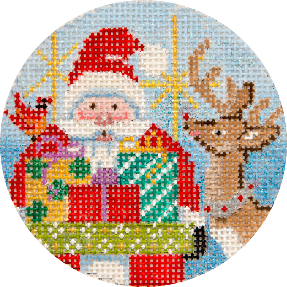 A circular needlepoint canvas featuring a festive holiday design with Santa Claus, a reindeer, gifts, and a bird on a light blue grid background.