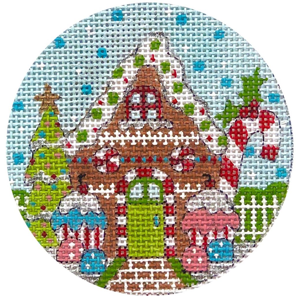 Cross-stitched gingerbread house design on a circular fabric swatch.