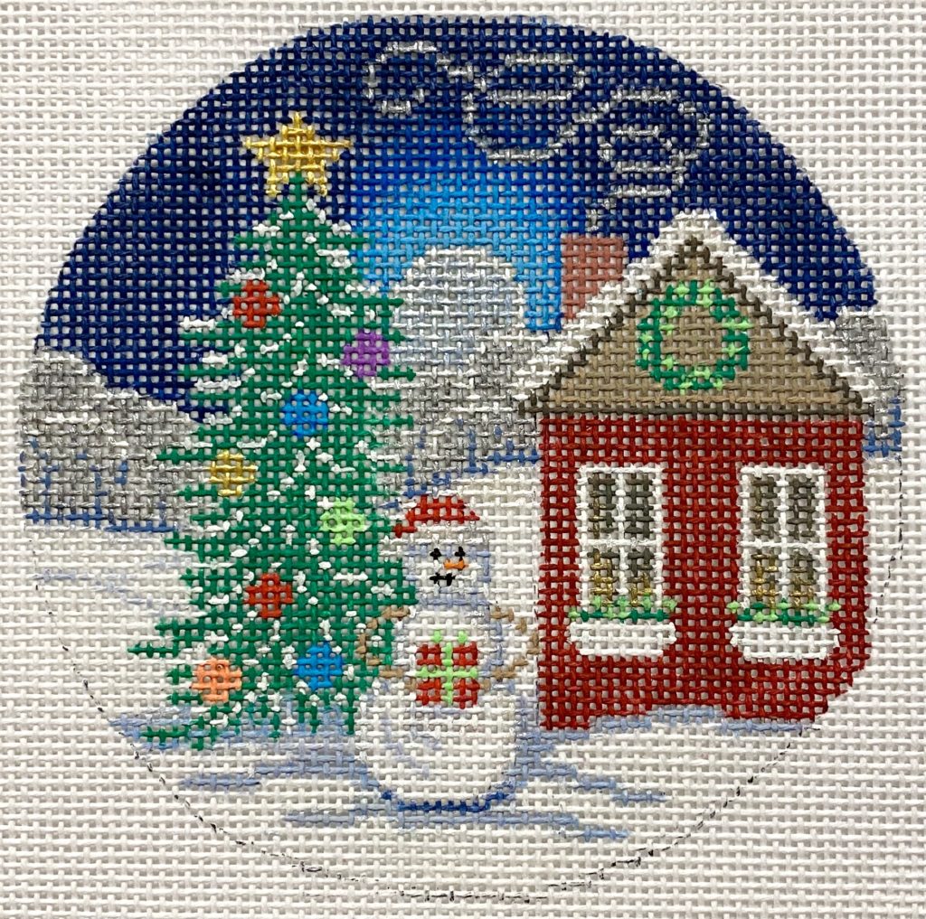 Decorative needlepoint of a snowy scene with a house, tree, and snowman.