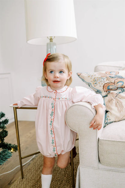 Young girl in a pink dress standing in a living room with a Christmas tree.