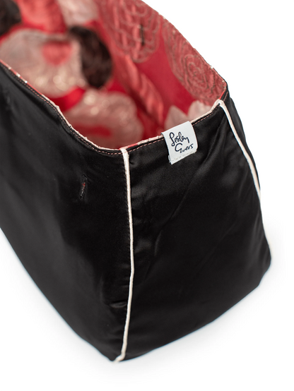 Black pet bed with red interior and a visible brand label on a white background