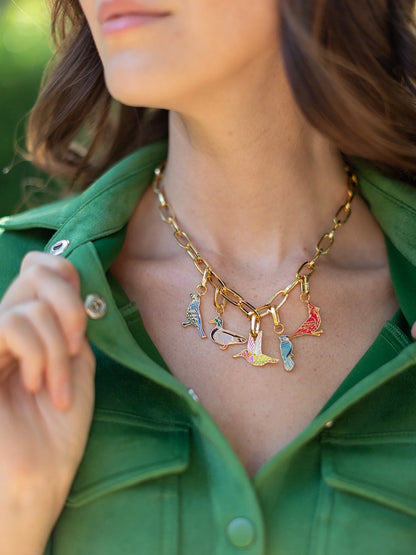 Woman wearing a gold chain necklace with colorful charms against a green background