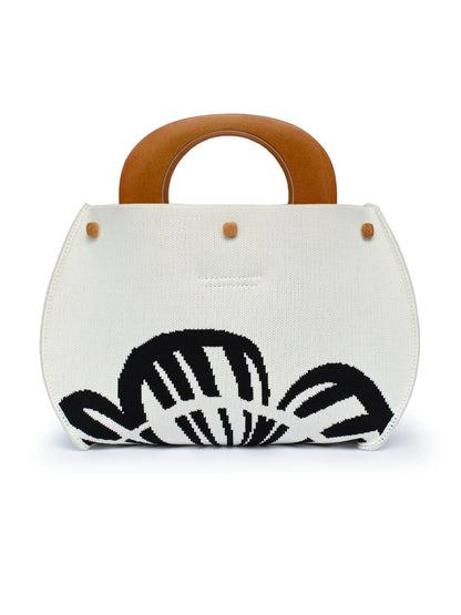 White handbag with black leaf pattern and wooden handle on a white background