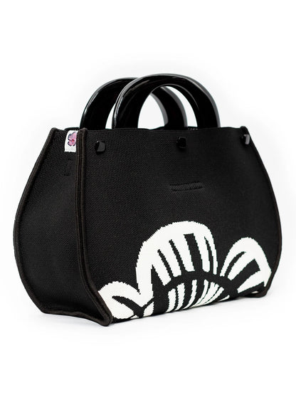 Black handbag with a white floral design on a white background