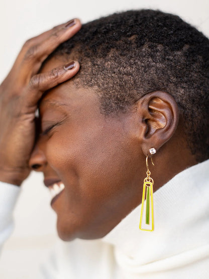 Woman with short hair wearing a gold earring with a yellow accent.