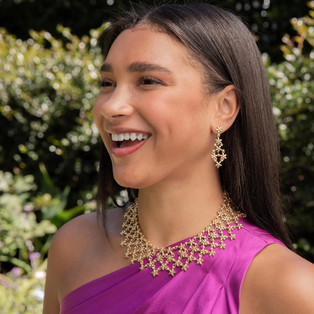 Woman wearing gold jewelry with a blurred green background