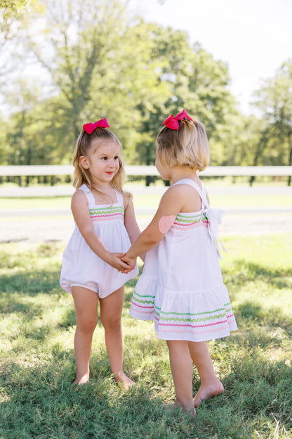 two children in white dresses hold hands outside
