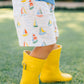 Child wearing yellow rain boots and patterned shorts on grass