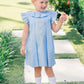 Young girl in a blue dress standing on a garden path.