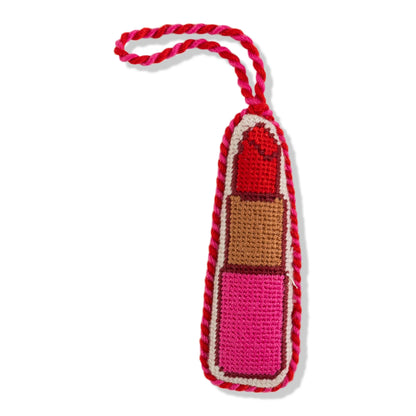 Crocheted lipstick-shaped toy with a red top and pink body on a white background