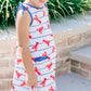 Young girl wearing a dress with red lobster pattern outdoors.