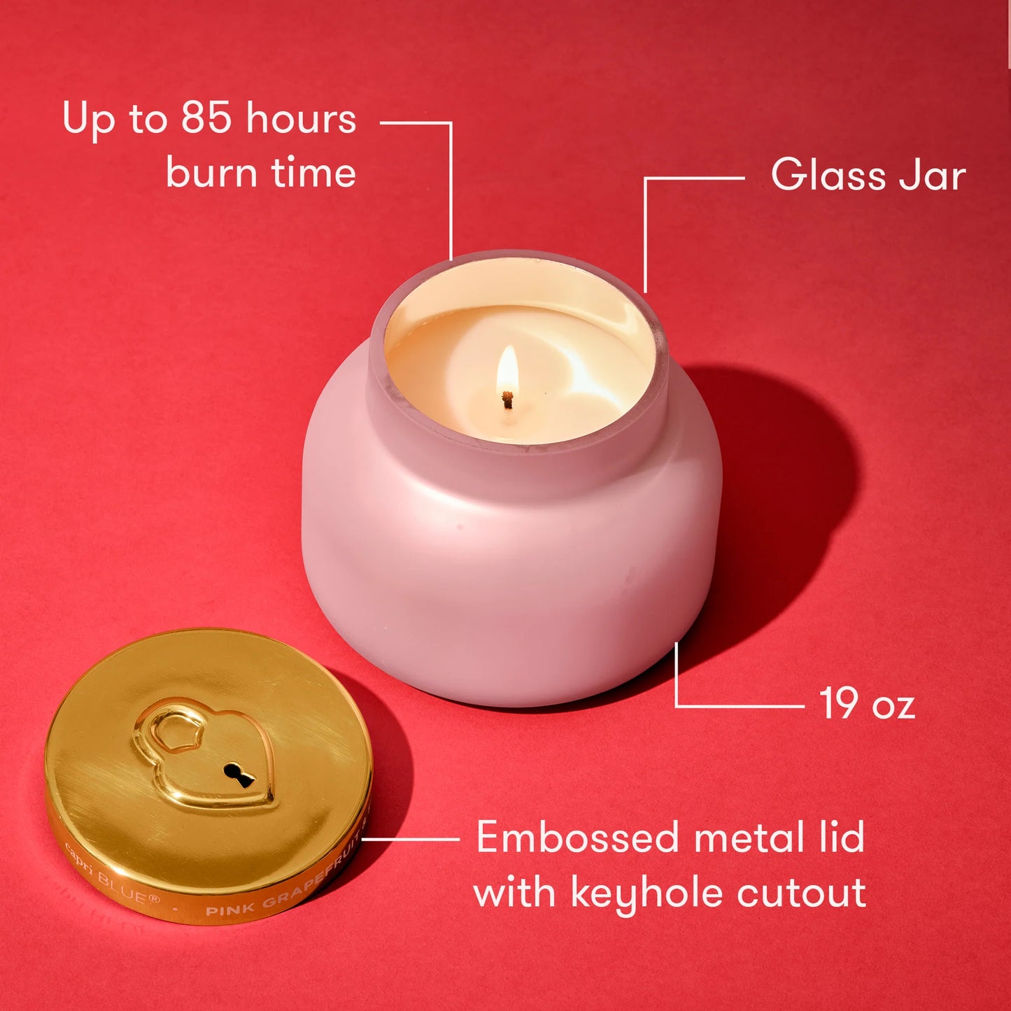 Pink candle in a glass jar with gold lid on a red background, showing features like burn time and weight.
