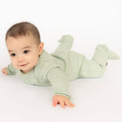 Baby wearing a green onesie on a white background