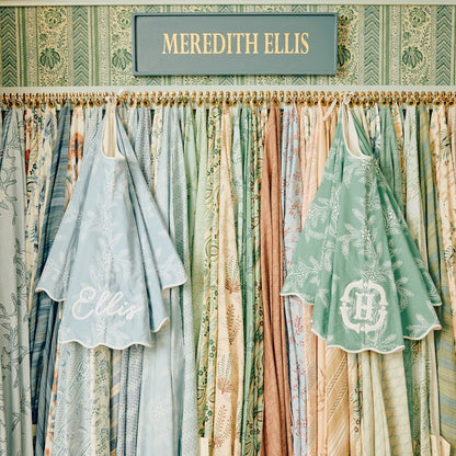 Vintage-style clothing with 'Ellis' branding against a patterned wall with 'MEREDITH ELLIS' sign.