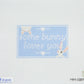 Cross-stitch pattern with 'some bunny loves you' text on a light blue background
