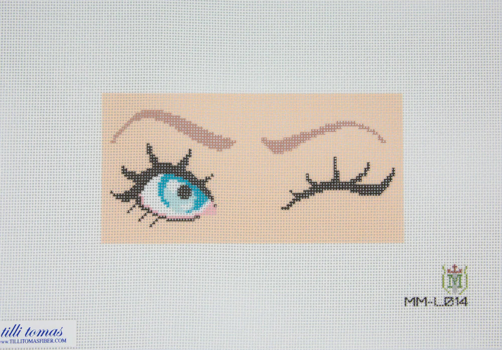 Cross-stitched design of an eye with eyelashes on a beige background, featuring the brand 'Milli Tomas' logo.