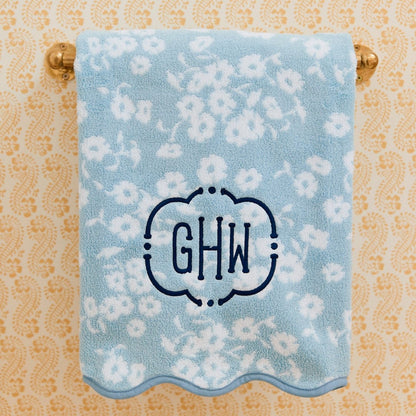 Floral patterned towel with monogram 'GHW' on a decorative towel rack.