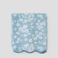 Folded blue fabric with white floral pattern on a light gray background