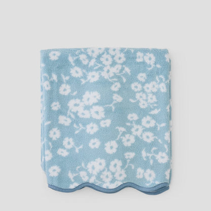 Folded blue fabric with white floral pattern on a light gray background