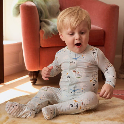 Child wearing a patterned onesie sitting on a rug with a red chair in the background
