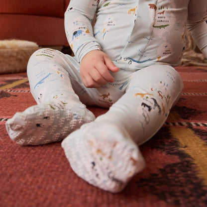 Baby wearing a onesie with a map design sitting on a patterned rug.