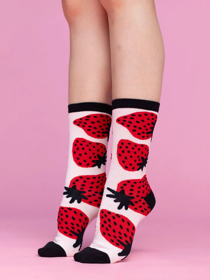 Socks with strawberry pattern worn by a person on a pink background