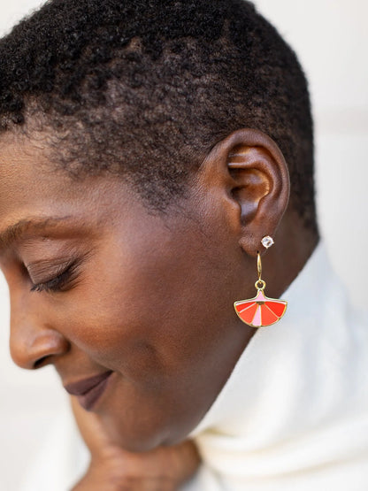 Close-up of a woman wearing a red and gold earring with a blurred background
