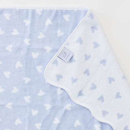 Baby blanket with heart pattern and brand tag on a light blue background
