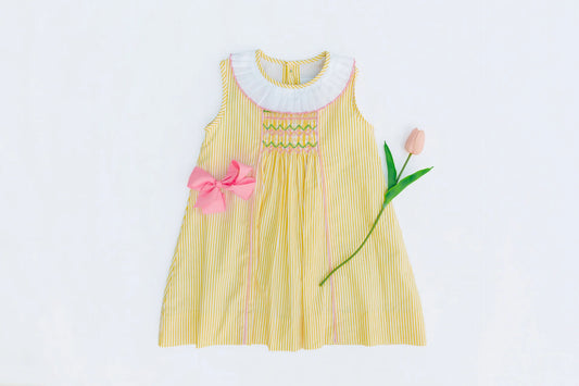 Yellow dress with pink bow and tulip on a white background