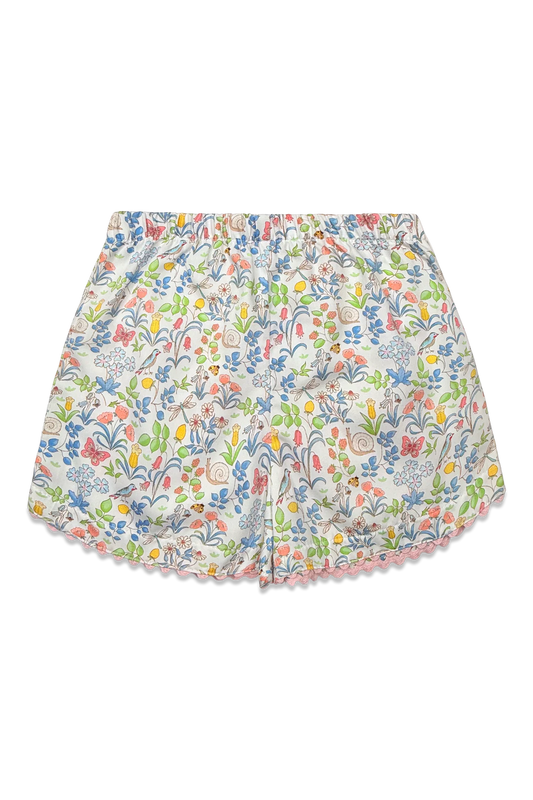 A pair of girl's shorts featuring an all-over multicolor floral print on a white base, finished with a delicate pink scalloped hem.