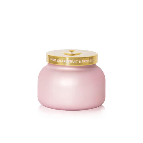 Pink candle with a gold lid on a white background