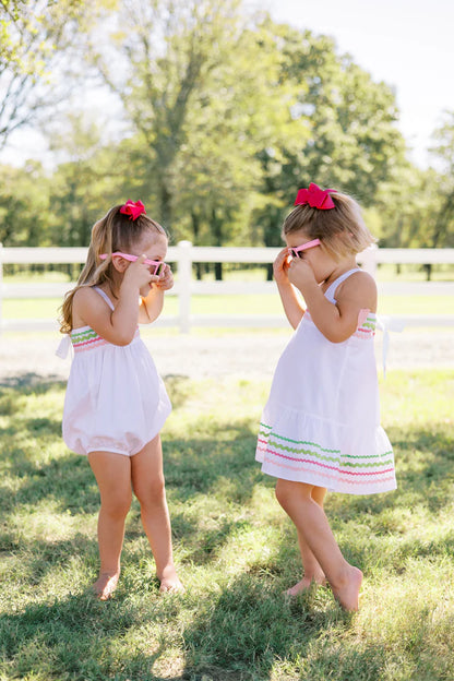 two children in white dresses hold hands outside